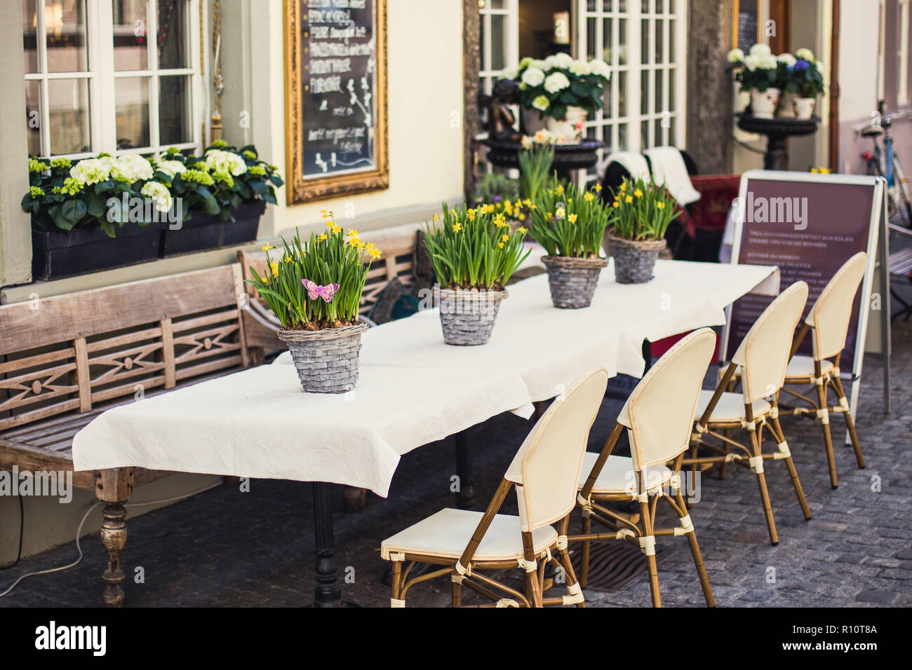 Сozy outdoor cafe in Europa con tovaglia bianca e cesti di fiori Foto Stock