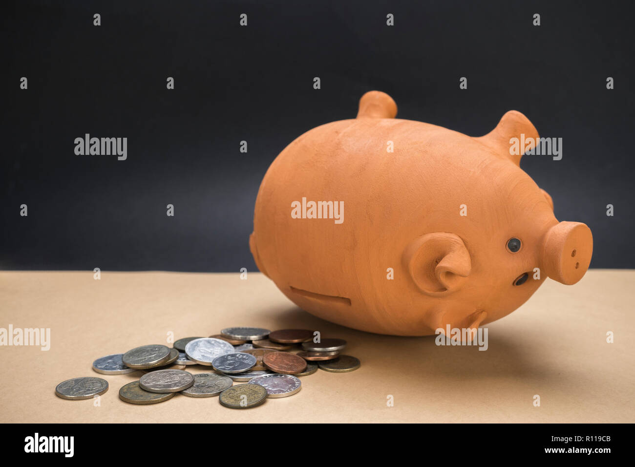 Salvadanaio di ceramica oggetto di dumping accanto a diverse monete, immagine concettuale Foto Stock
