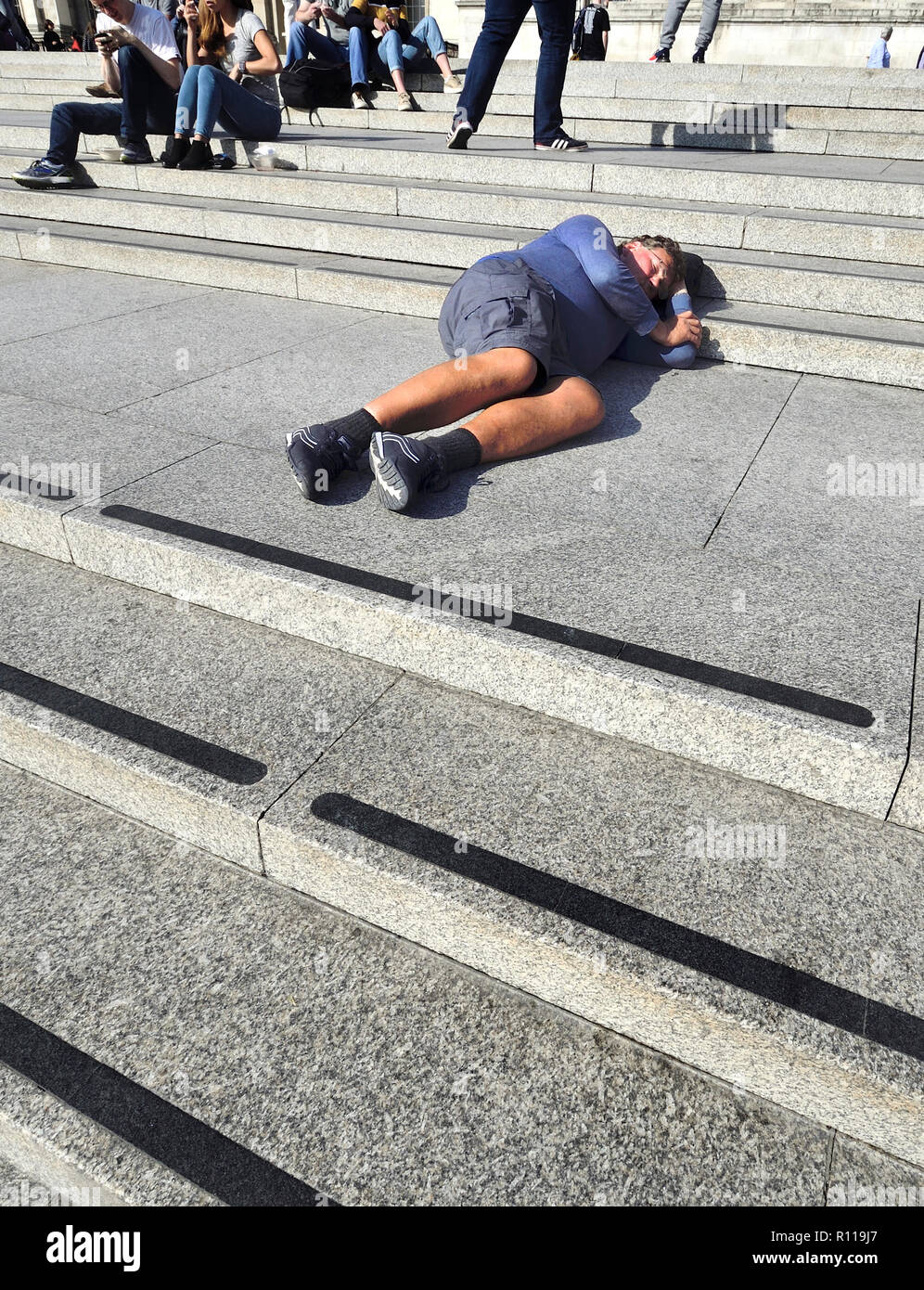 Uomo di dormire su i passi fino alla National Gallery in Trafalgar Square a Londra, Inghilterra, Regno Unito. Foto Stock