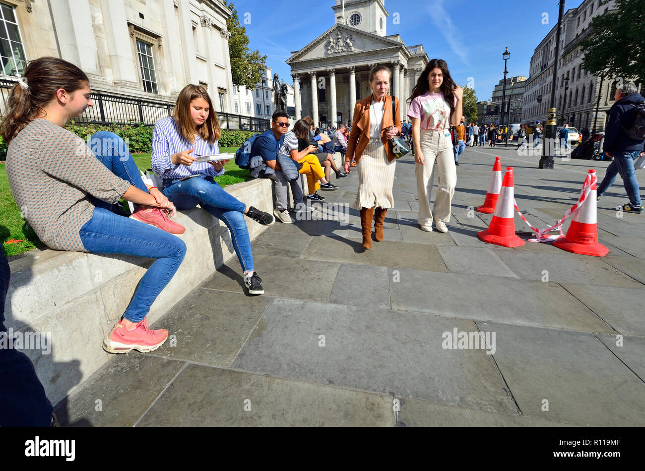 Le persone in un momento di relax a ora di pranzo di fronte alla National Gallery in Trafalgar Square a Londra, Inghilterra, Regno Unito. Foto Stock