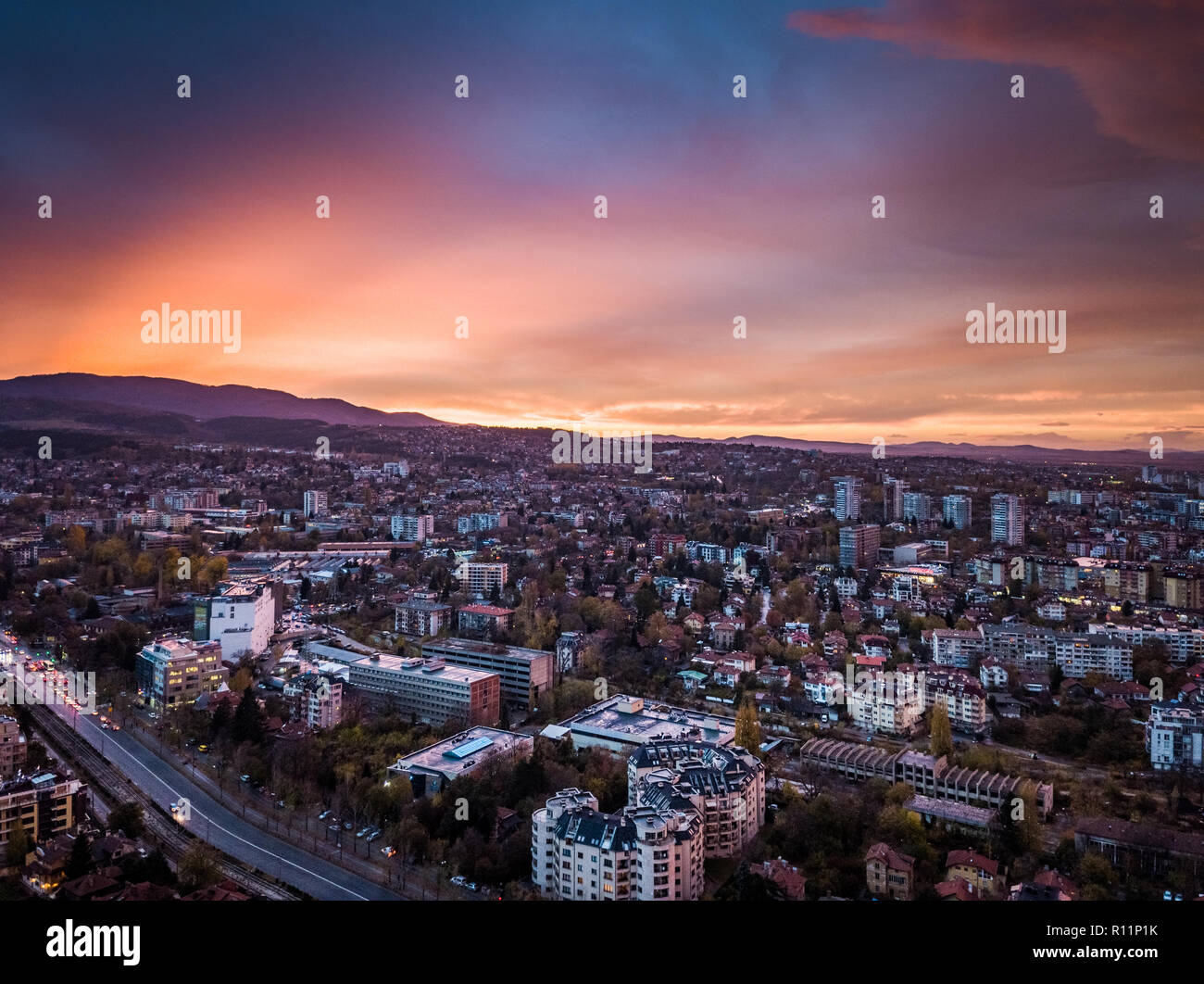 Bella drone shot sulla città di Sofia presso sunrise - sorprendenti immagini brillanti con colorati cieli, sfondo montano e tipico paesaggio urbano Foto Stock