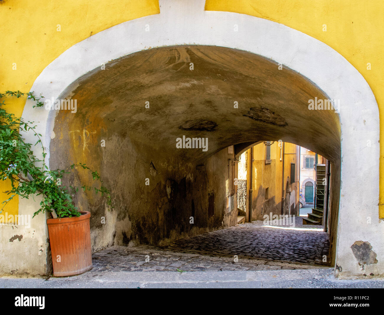 Caratteristico vicolo coperto nel borgo medievale di Tuscania (Italia) con parete gialla in primo piano. Foto Stock