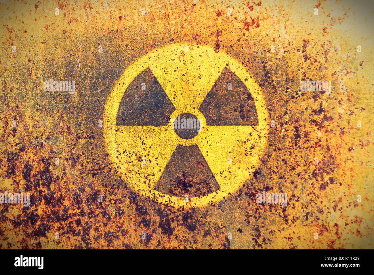 Giallo rotondo radioattivo (radiazioni ionizzanti) simbolo di pericolo dipinta su un massiccio metallo arrugginito parete con rustico texture grunge background. Lavata allo sbiadimento Foto Stock