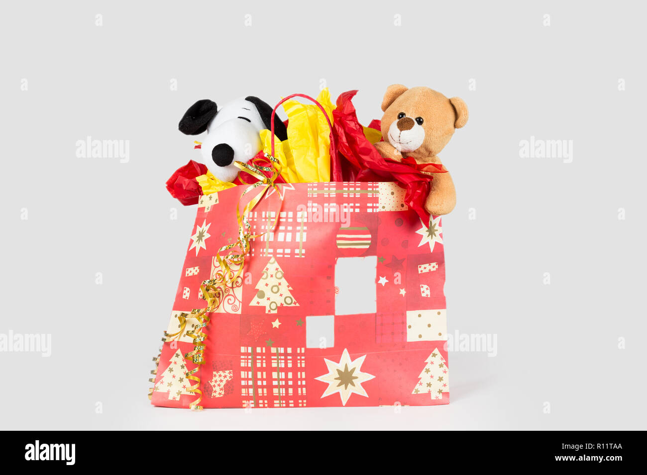 Giocattoli imbottiti avvolto con della carta e a saltare da una borsa regalo Foto Stock