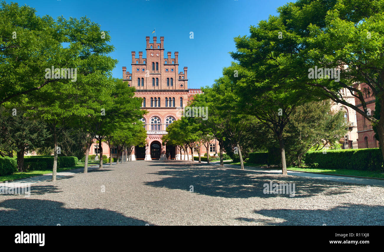 La facciata anteriore della capmus principale di Yuriy Fedkovych Chernivtsi Università Nazionale contro lo sfondo del giardino con alberi verdi e hedge. Foto Stock