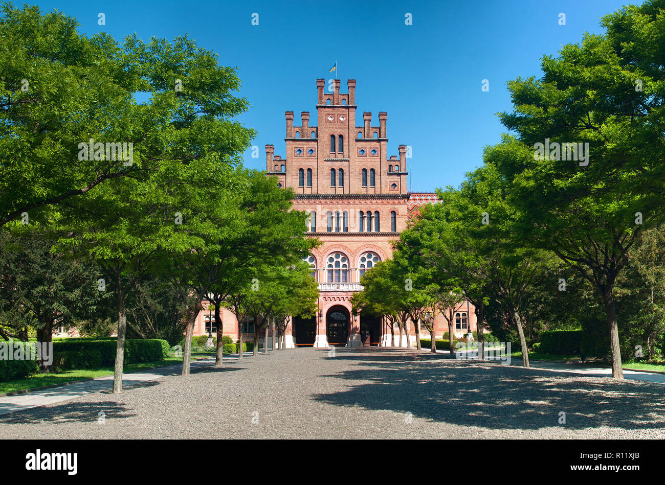 La facciata anteriore della capmus principale di Yuriy Fedkovych Chernivtsi Università Nazionale contro lo sfondo del giardino con alberi verdi e hedge. Foto Stock