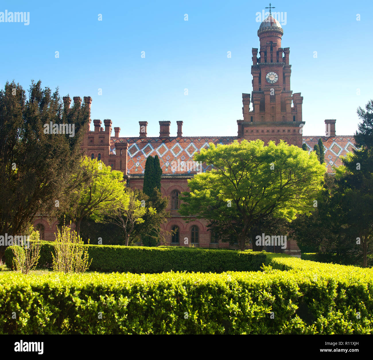 Parte di Yuriy Fedkovych Chernivtsi Università Nazionale contro lo sfondo del giardino con alberi verdi e hedge. L'edificio in Eclect Foto Stock