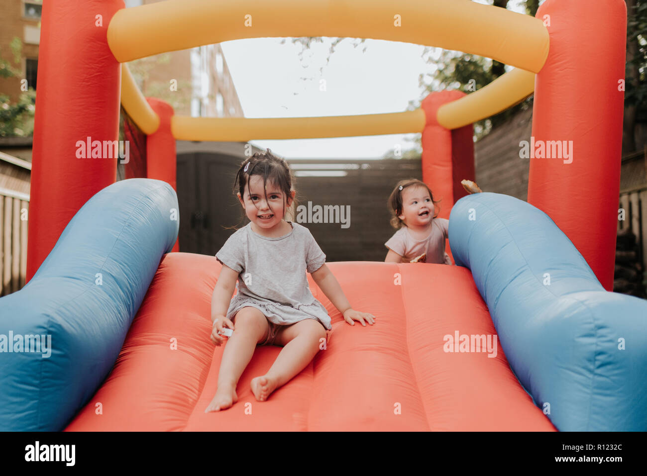 Sorelle giocando sulla slitta gonfiabile Foto Stock