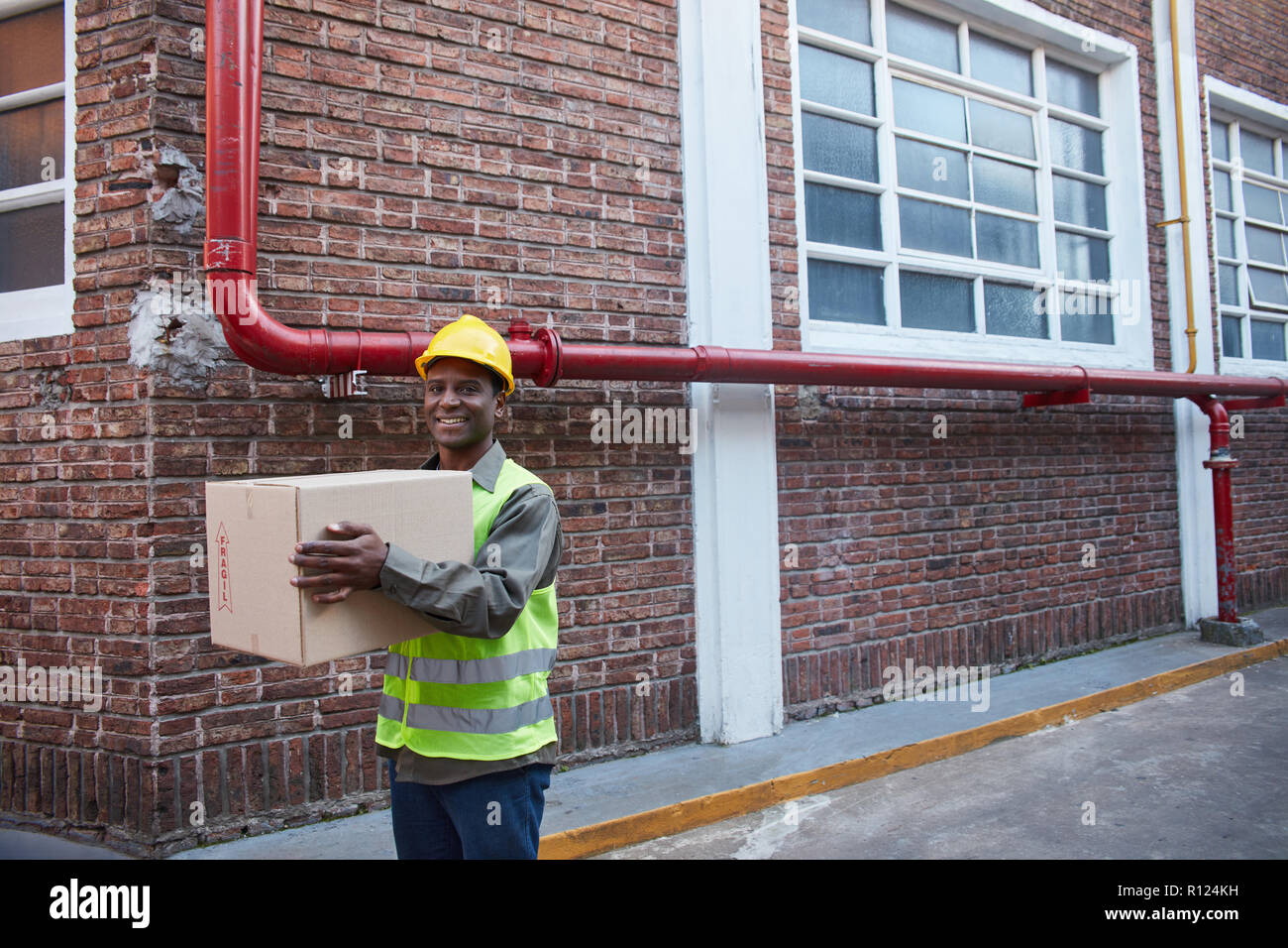 Lavoratore africano di fronte alla logistica del centro di spedizione porta un pacchetto Foto Stock