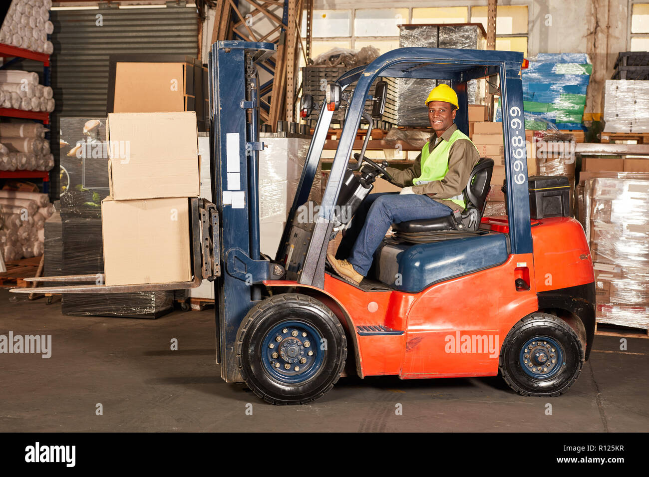 Lavoratore trasporta consegna con carrello in centro di spedizione Foto Stock