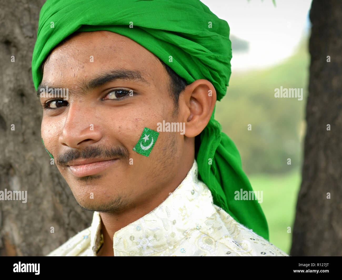 Giovani Musulmani indiani uomo con una verde bandiera islamica dipinto sul suo volto indossa un velo di colore verde durante la Rabi' al-awwal festeggiamenti. Foto Stock