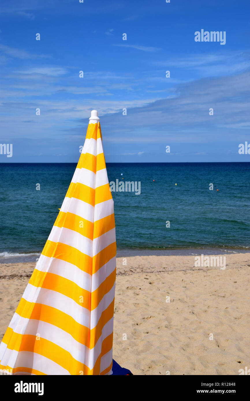 Ombrellone sulla spiaggia, chiusa gialla e bianca a strisce ombrello sul  mare mediterraneo come uno sfondo per accessori da spiaggia Foto stock -  Alamy