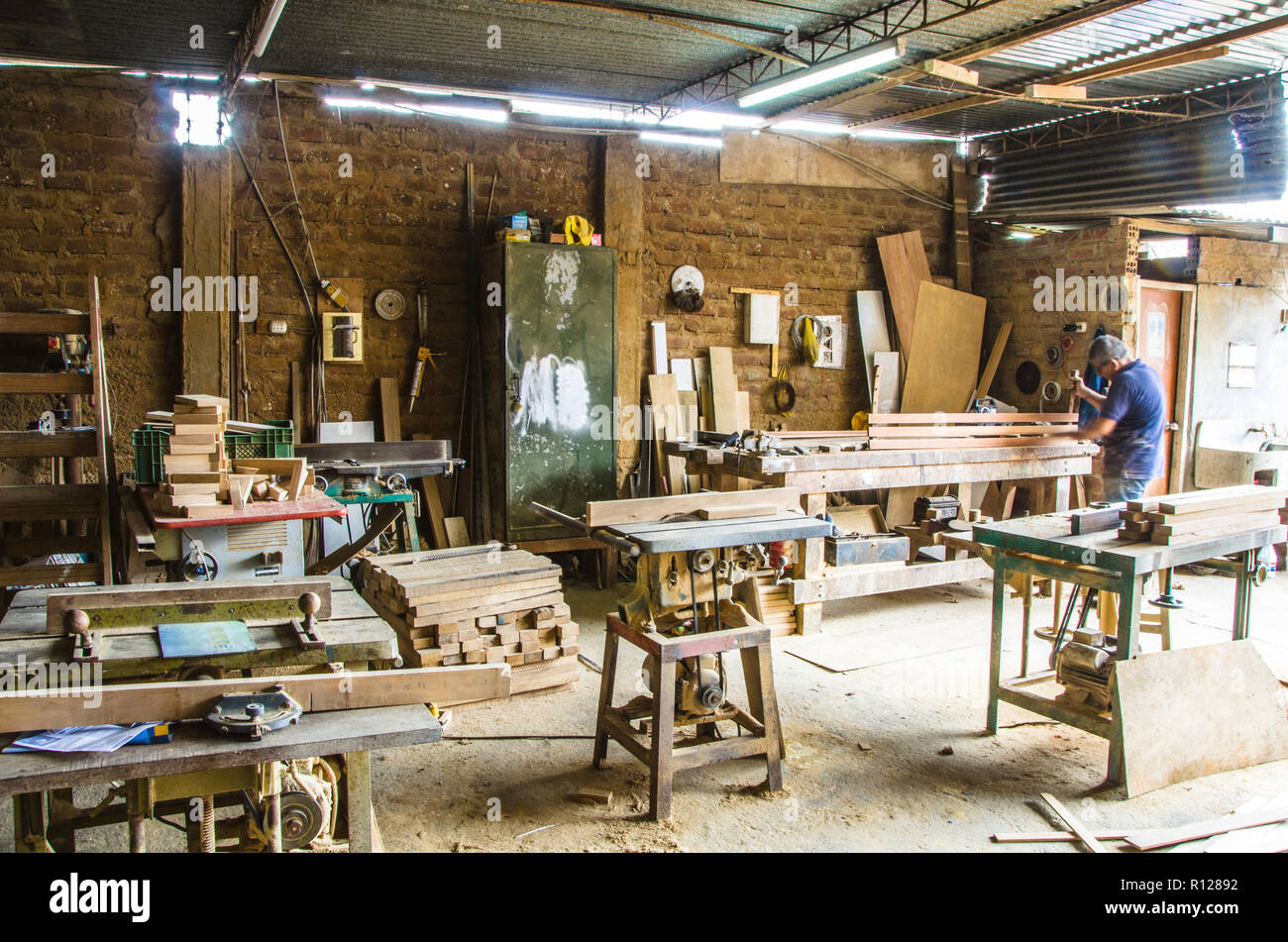 L'uomo facendo lavori in legno in falegnameria. Laboratorio di falegnameria. Carpenter lavorando su asse di legno in officina. Foto Stock