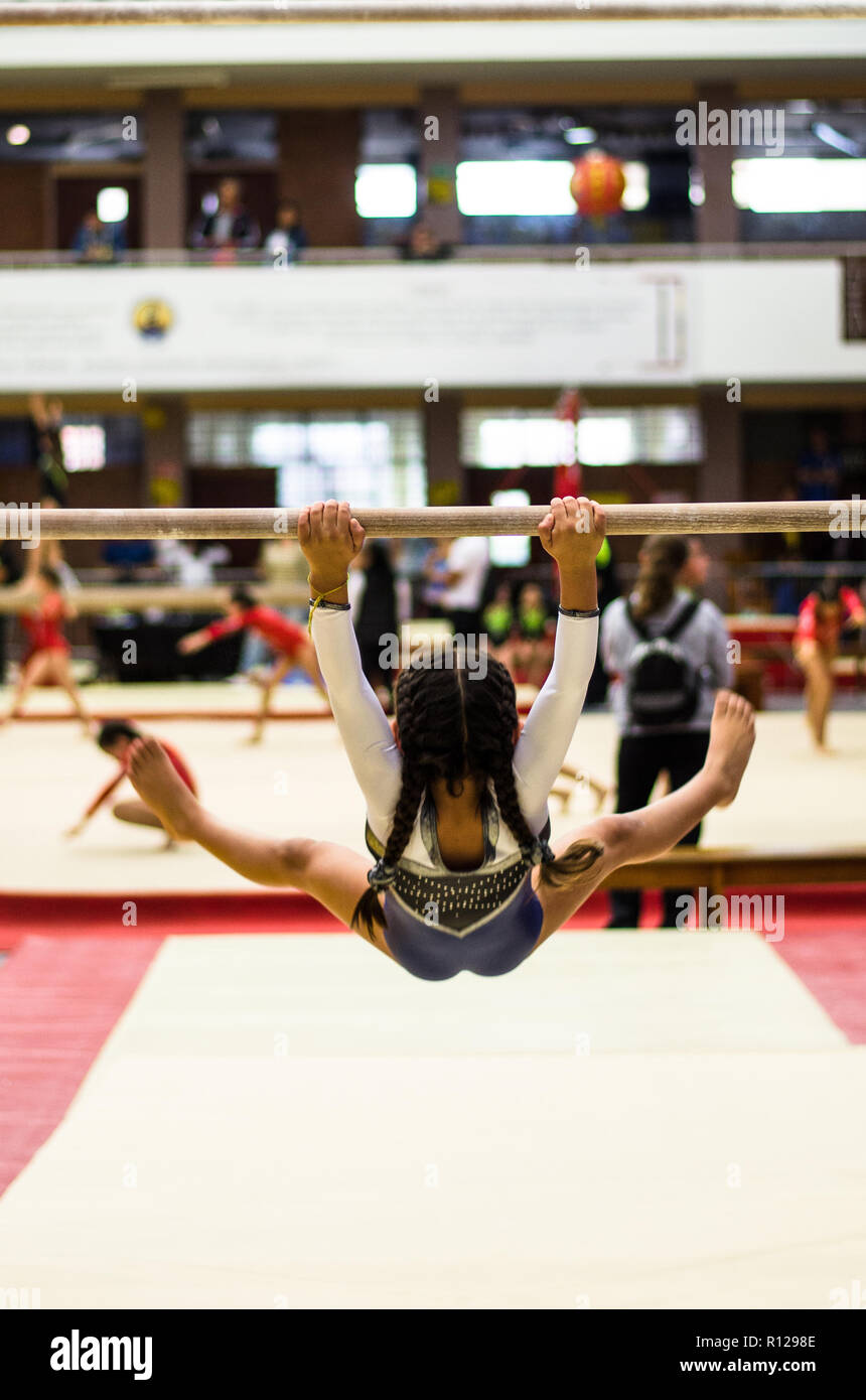 Athletic bambina ginnasta eseguire esercizi al bar in campionato Foto Stock