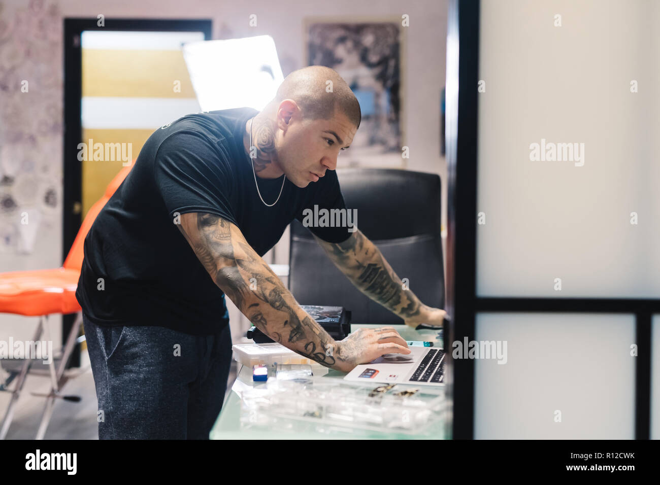 Tattooist utilizzando laptop in salotto Foto Stock