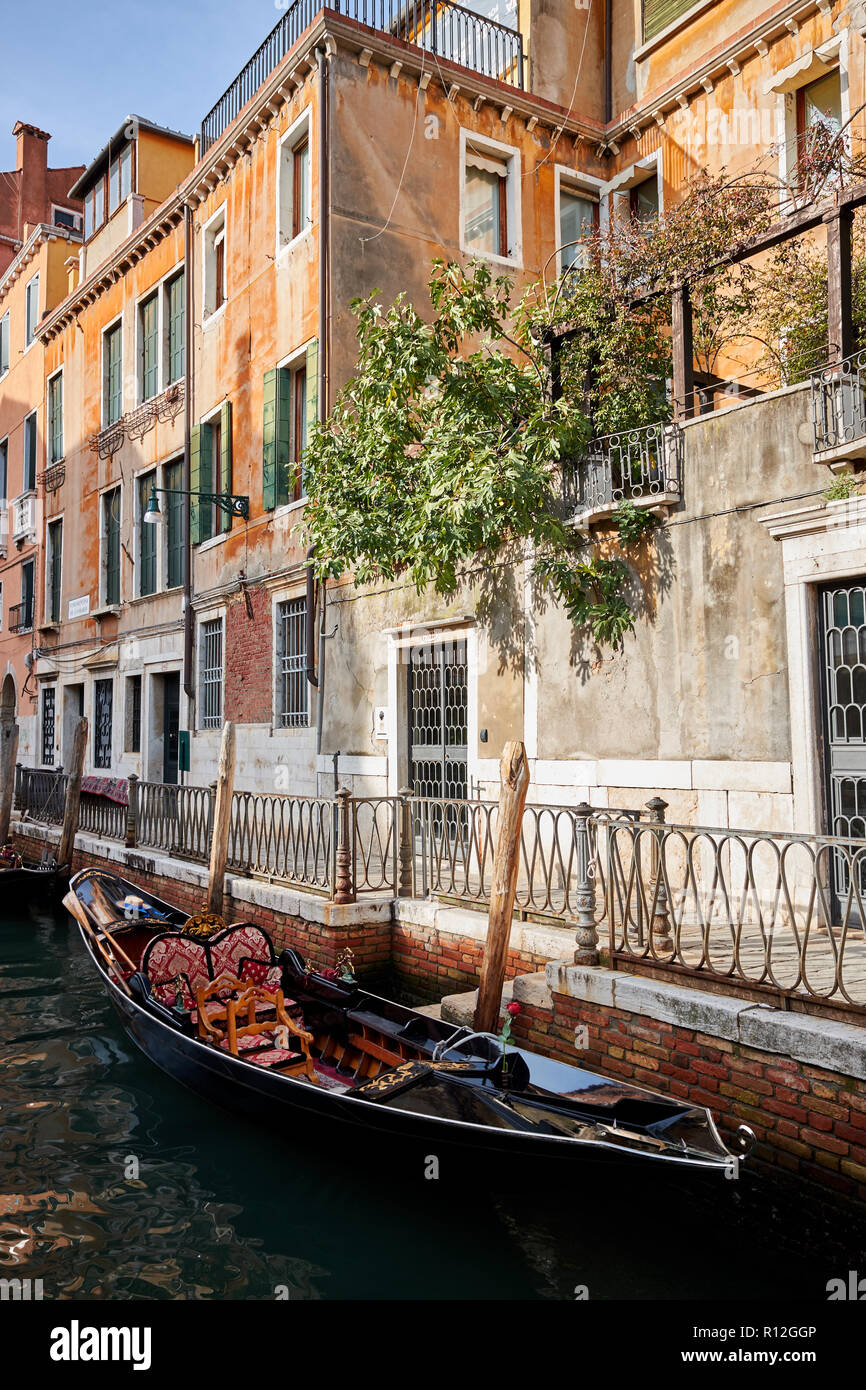 Un tradizionale gondola ormeggiata a lato di un canale veneziano accanto a riscaldare edifici colorati Foto Stock