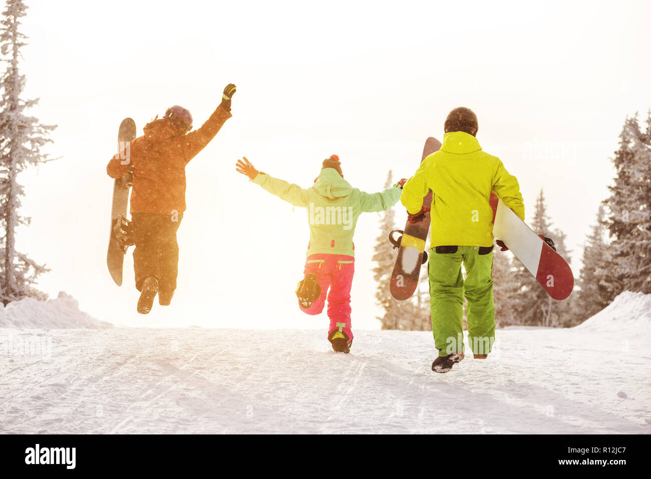 Gruppo di tre amici felici gli snowboarder si divertono e corre alla pista da sci con racchette da neve Foto Stock