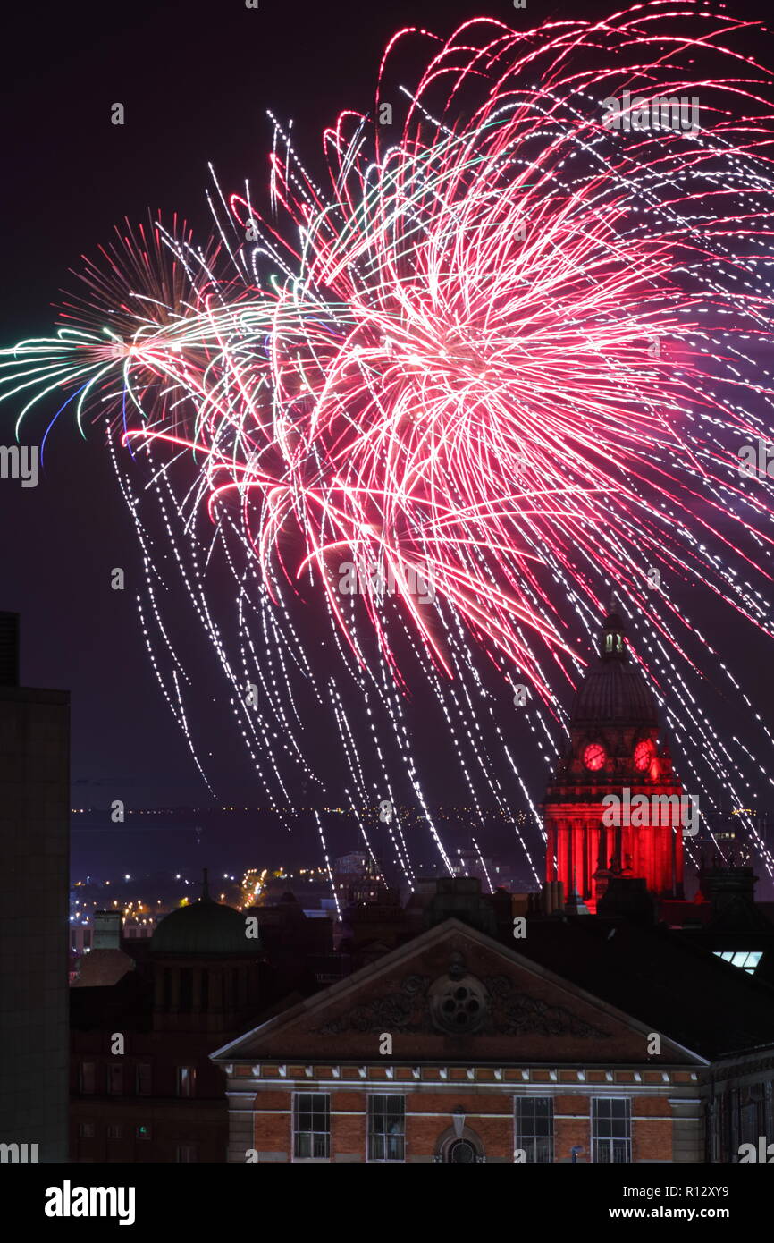 Leeds 8 novembre 2018. Fuochi d'artificio dal Leeds Interruttore Luci su illuminano il cielo notturno dietro Leeds Town Hall illuminato di rosso per il Leeds International Film Festival. Foto Stock