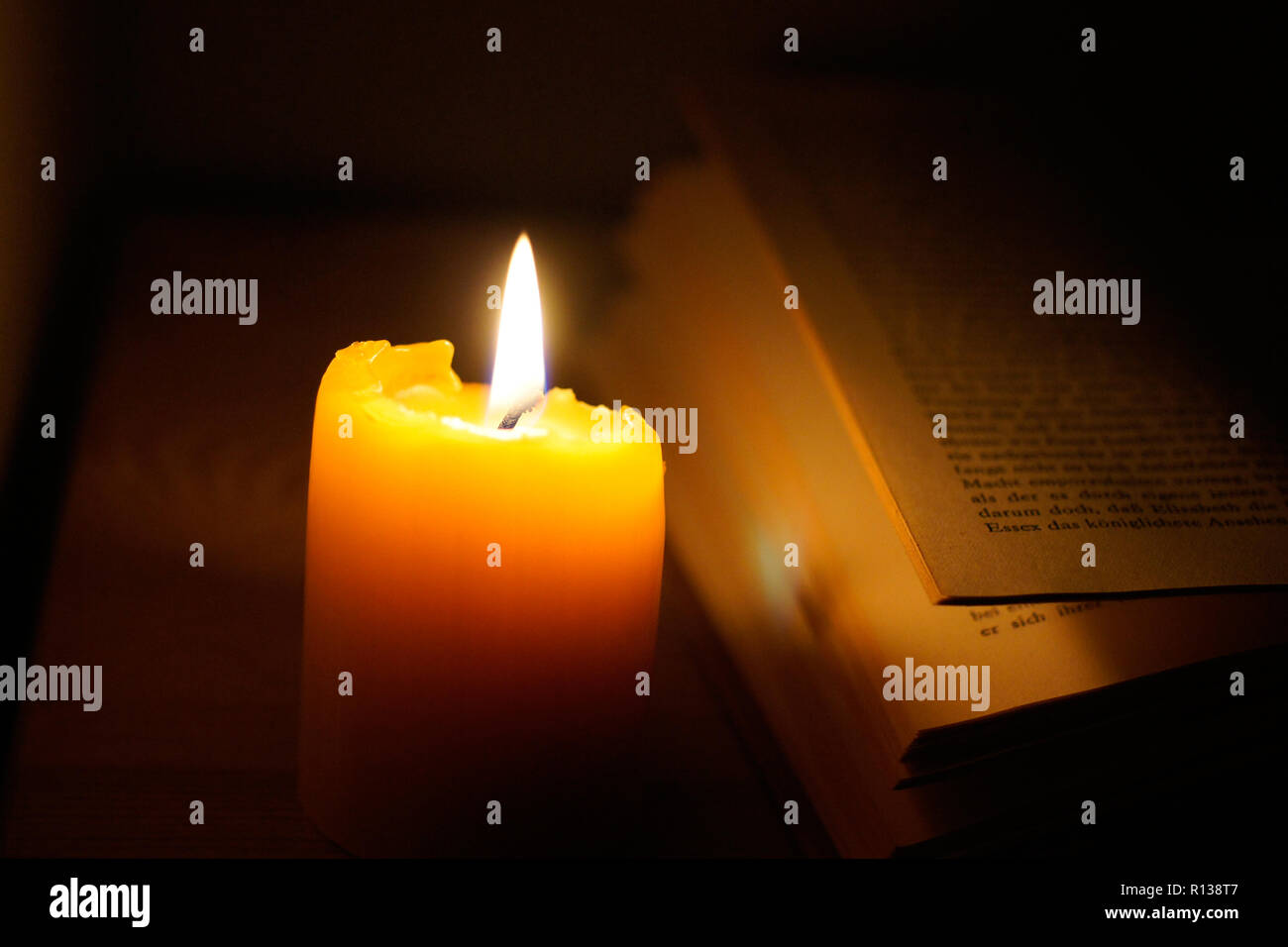 Splendida candela nel buio vicino al vecchio libro Foto Stock