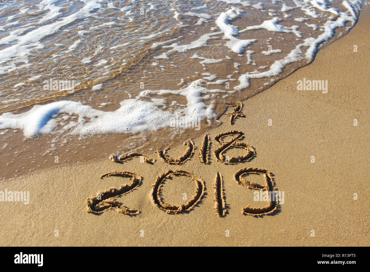 2019, 2018 e 2017 anni scritto sulla spiaggia di sabbia di mare. Wave lava via 2017, 2018. Foto Stock