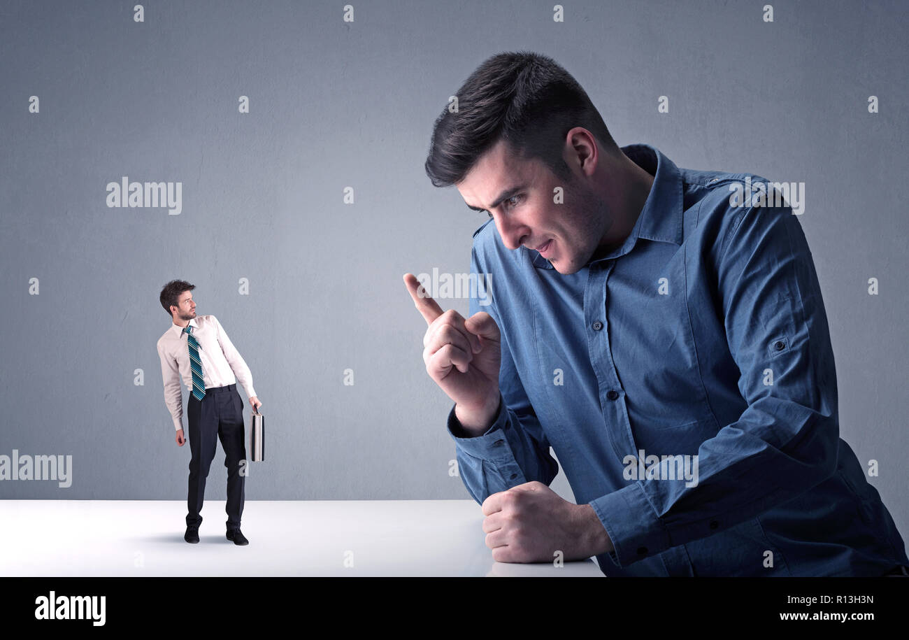 Giovane imprenditore professionale essendo arrabbiato con un altro imprenditore in miniatura Foto Stock