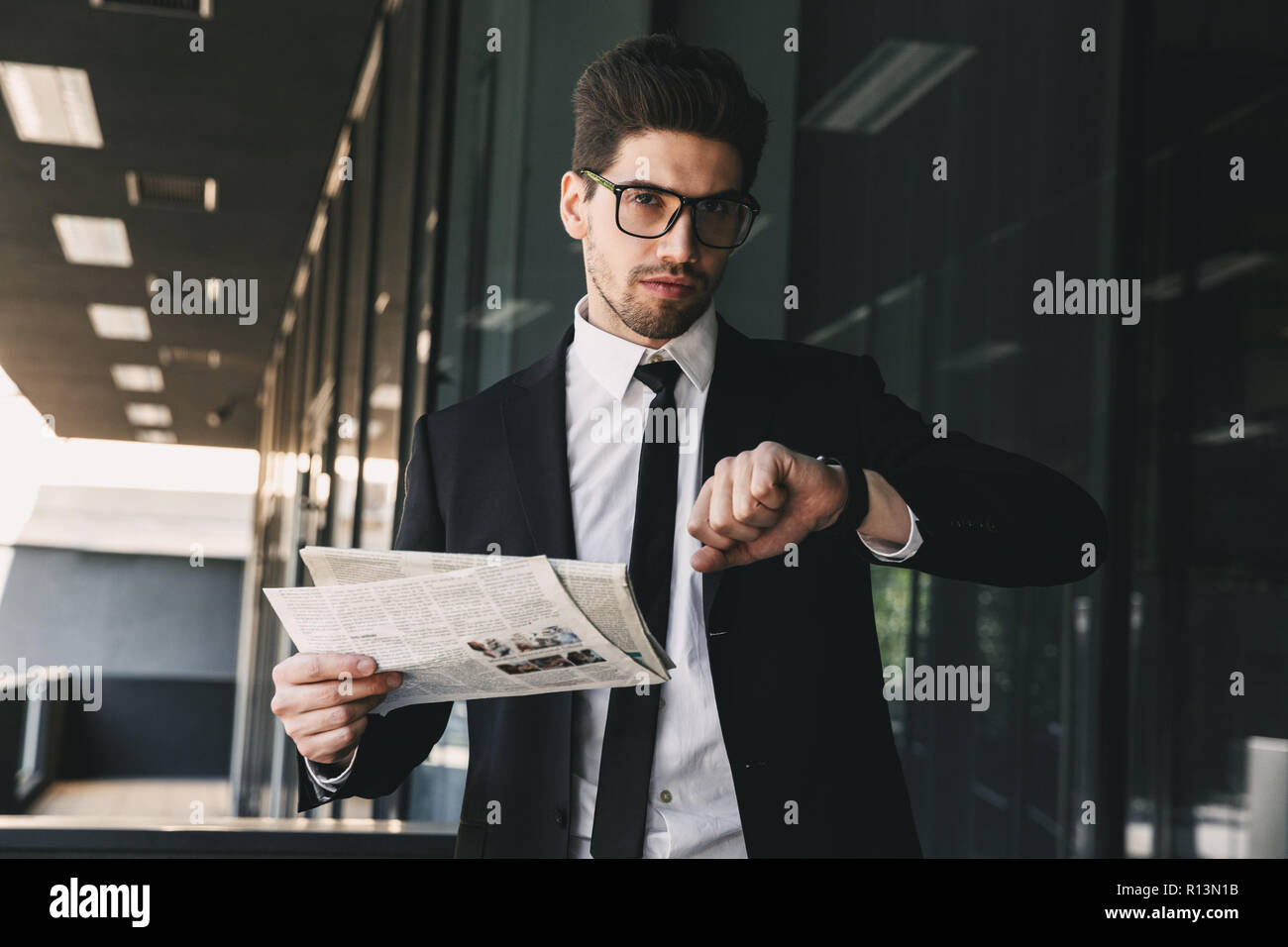 Immagine del bel business man holding giornale guardando watch orologio. Foto Stock