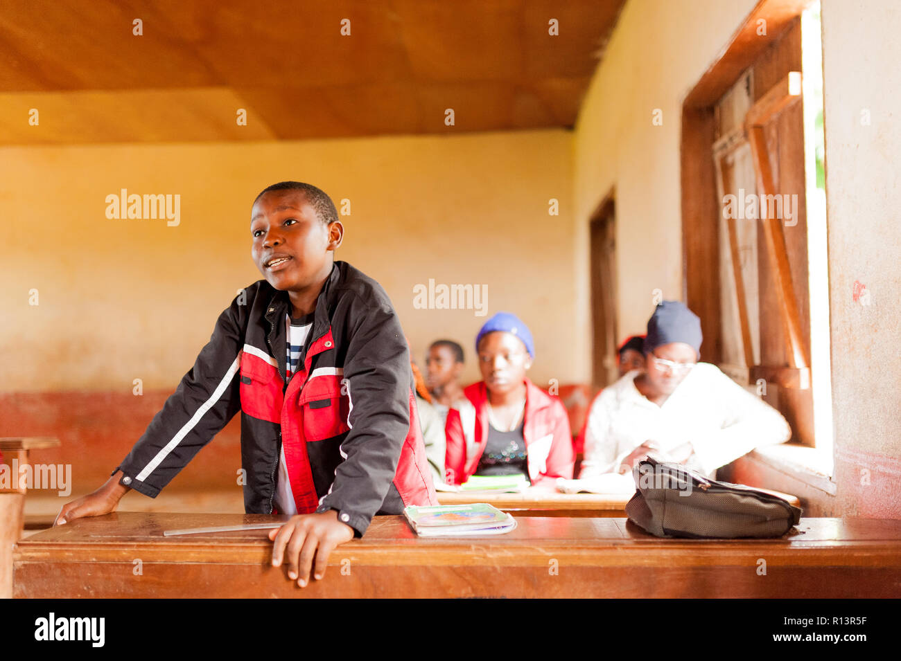 Bafoussam, Camerun - 06 agosto 2018: sorridente bambino africano alzarsi in Aula parlando con insegnante durante la lezione in villaggio Foto Stock