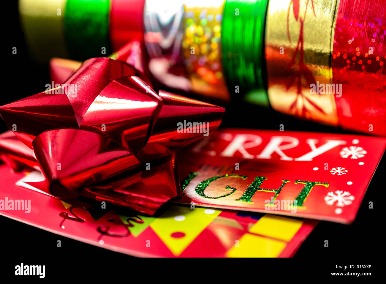 Un (1) raso rosso Natale nastro di prua con Natale carta da imballaggio e da regalo Tage. Camera per copia. Foto Stock