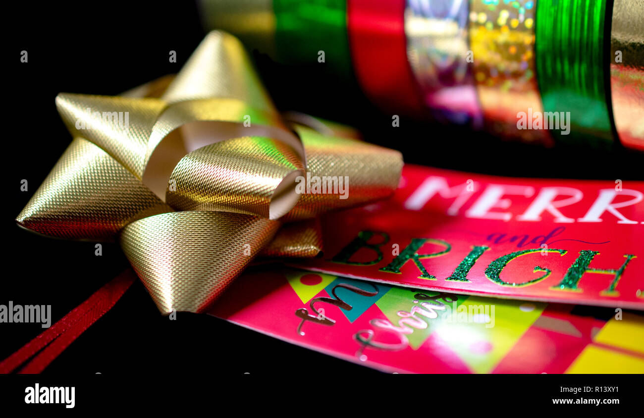 Un (1) Oro satinato Natale nastro di prua con Natale carta da imballaggio e da regalo Tage. Camera per copia. Foto Stock