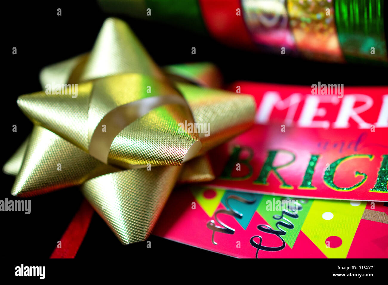 Un (1) Oro satinato Natale nastro di prua con Natale carta da imballaggio e da regalo Tage. Camera per copia. Foto Stock