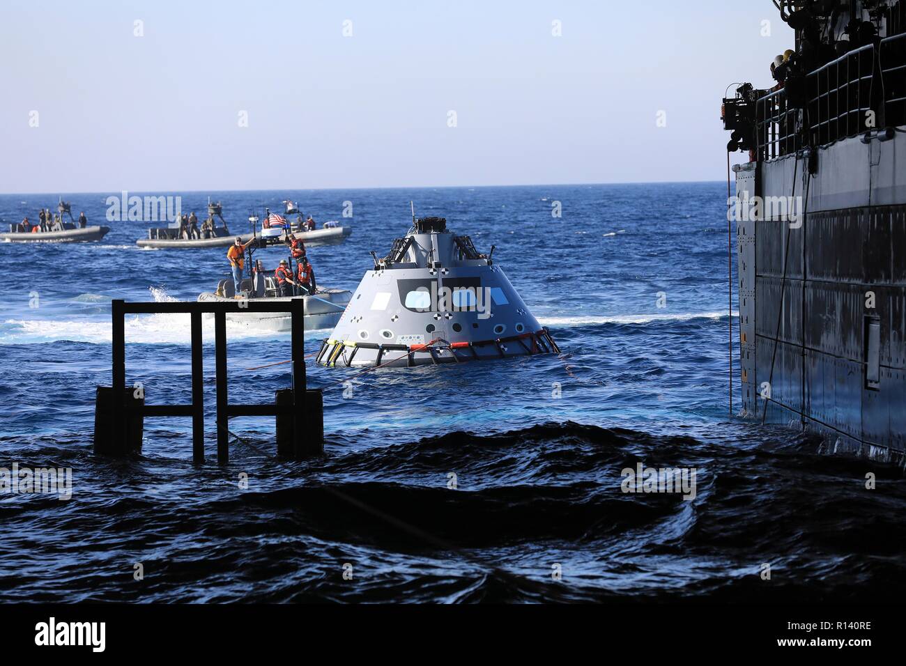 La NASA squadra di recupero e U.S. Navy divers tirare un mock up versione di Orion la generazione successiva capsula spaziale nel bene del ponte della USS John P. Murtha durante un oceano aperto prova di recupero 31 ottobre 2018 nell'Oceano Pacifico. La NASA e gli Stati Uniti La marina non ha eseguito oceano aperto il recupero di un manned space capsule poiché il progetto Apollo negli anni sessanta e sono le procedure di test e la bulloneria che verranno utilizzate per recuperare il veicolo spaziale Orion dopo che schizza verso il basso nell'Oceano Pacifico seguendo il futuro dello spazio profondo missioni di esplorazione. Foto Stock
