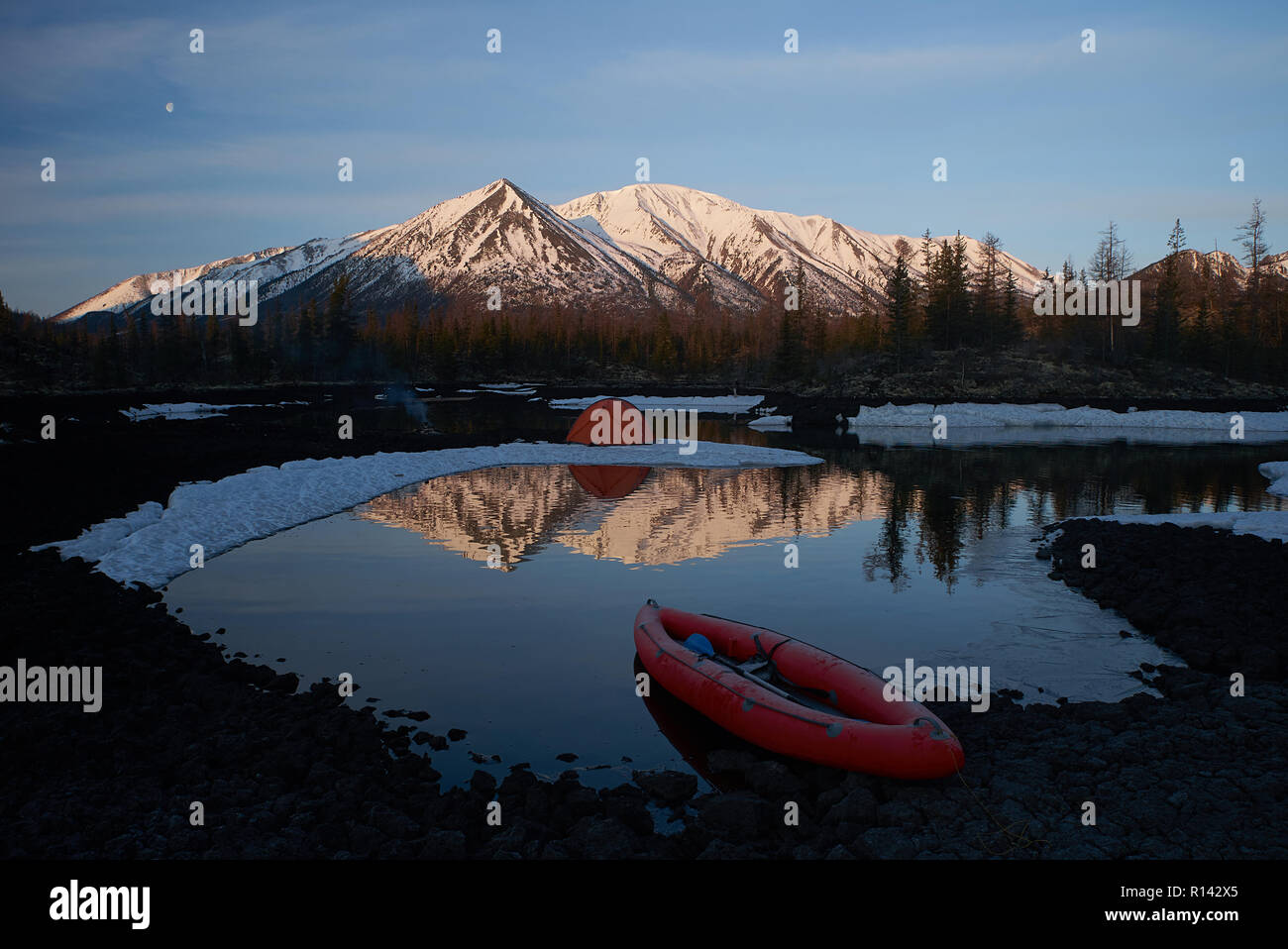 Campeggio con tenda arancione e canoa sul lago Foto Stock