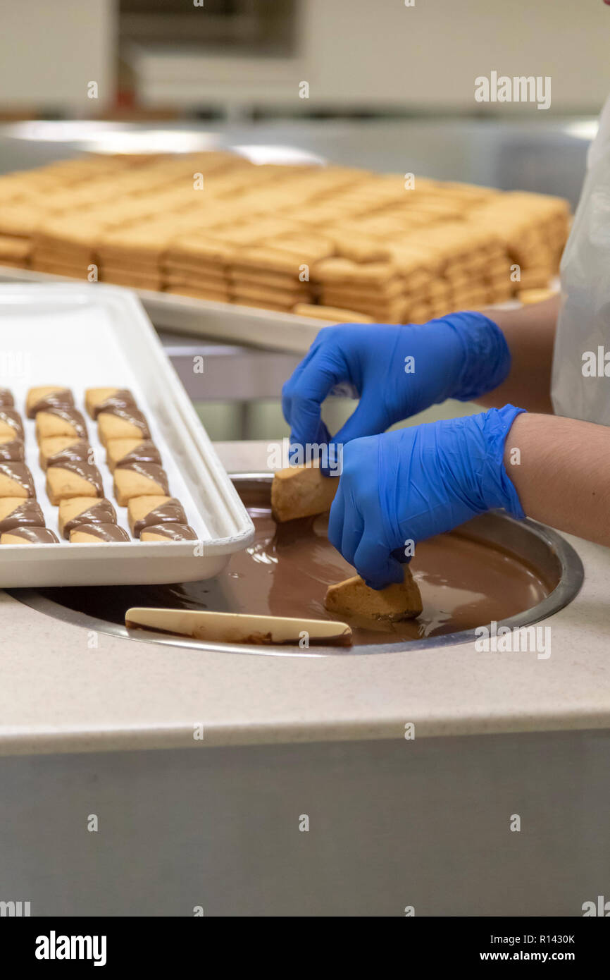 Hilo, Hawaii - i lavoratori fanno di noce Macadamia frollini immersi nel cioccolato al latte a Big Island delle caramelle. Foto Stock