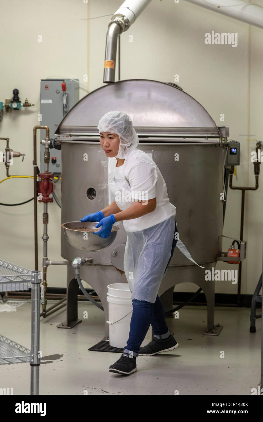 Hilo, Hawaii - un lavoratore svolge una tazza di cioccolato al latte fuso a Big Island delle caramelle. Foto Stock