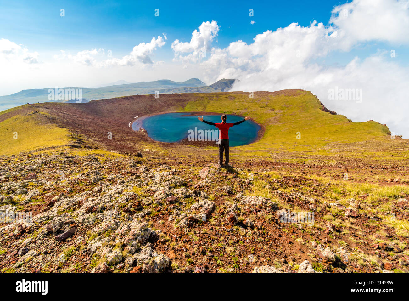Uomo al vertice del vulcano Azhdahak guardando il cratere del lago, Geghama mountains, Armenia Foto Stock