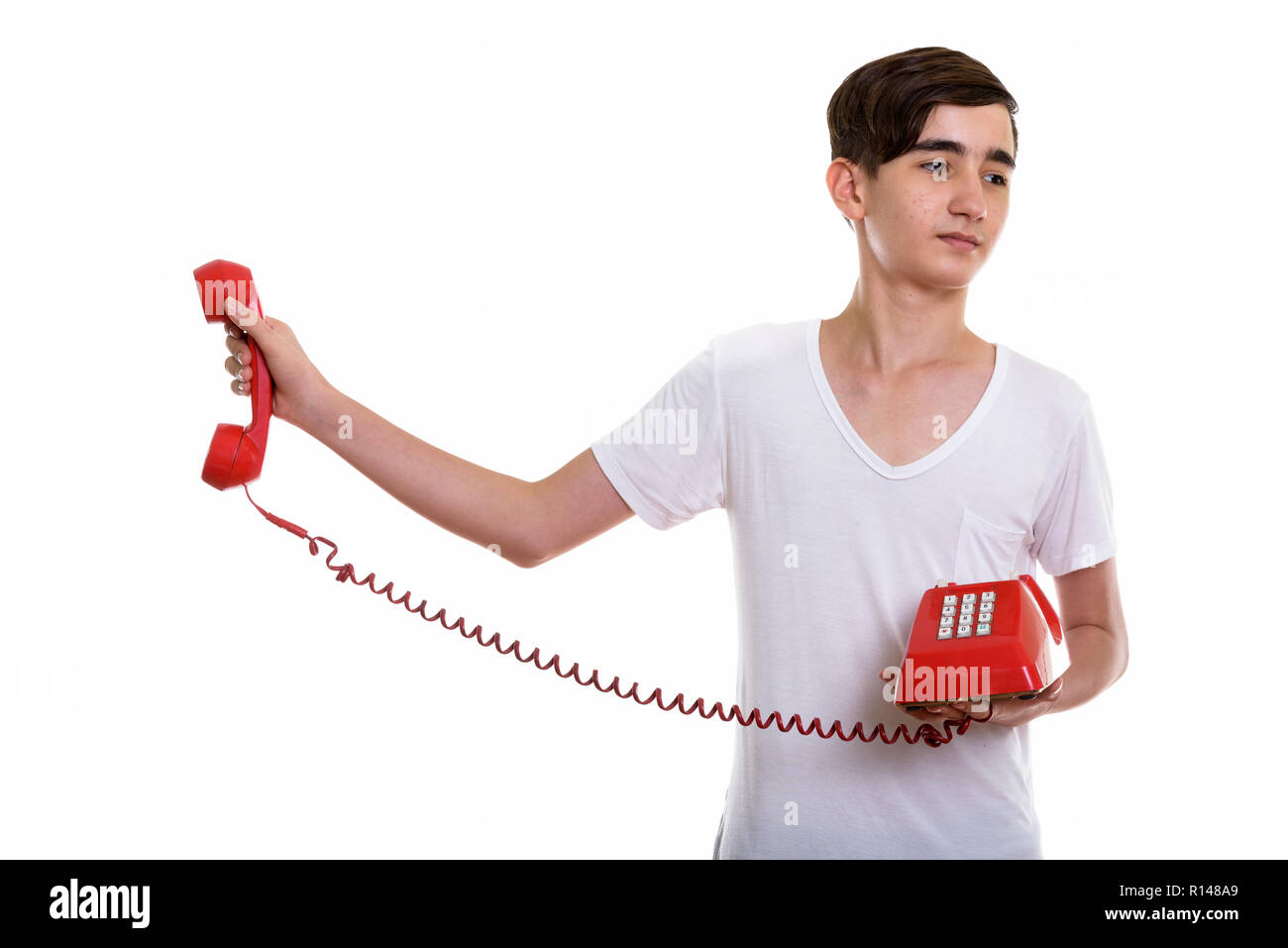 Studio shot di giovani ha sottolineato il persiano ragazzo adolescente tenendo il vecchio te Foto Stock