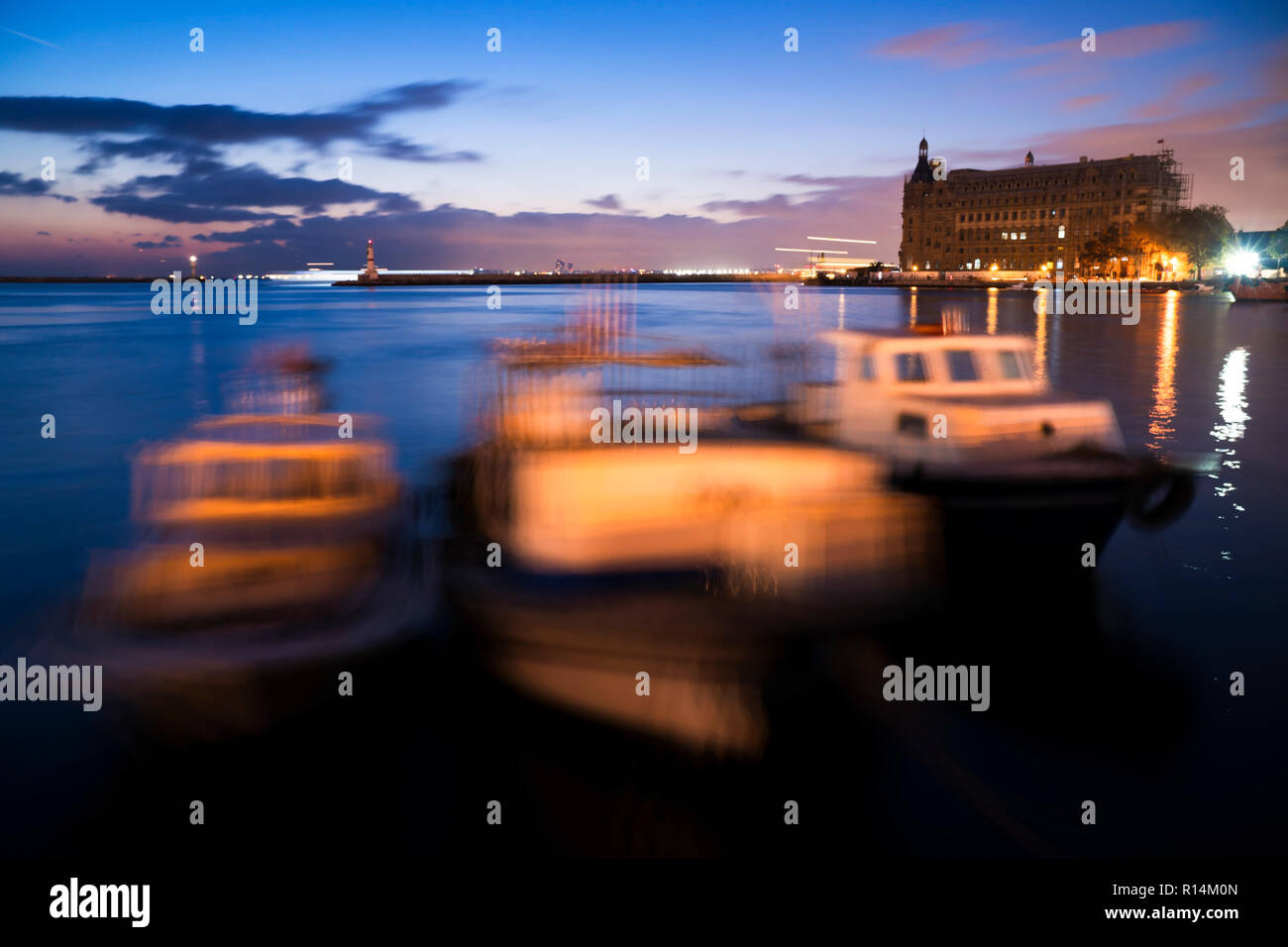 Exposured lunghe barche da pesca e di Haydarpasa Train Station Building a Istanbul Kadikoy dopo il tramonto. Foto Stock