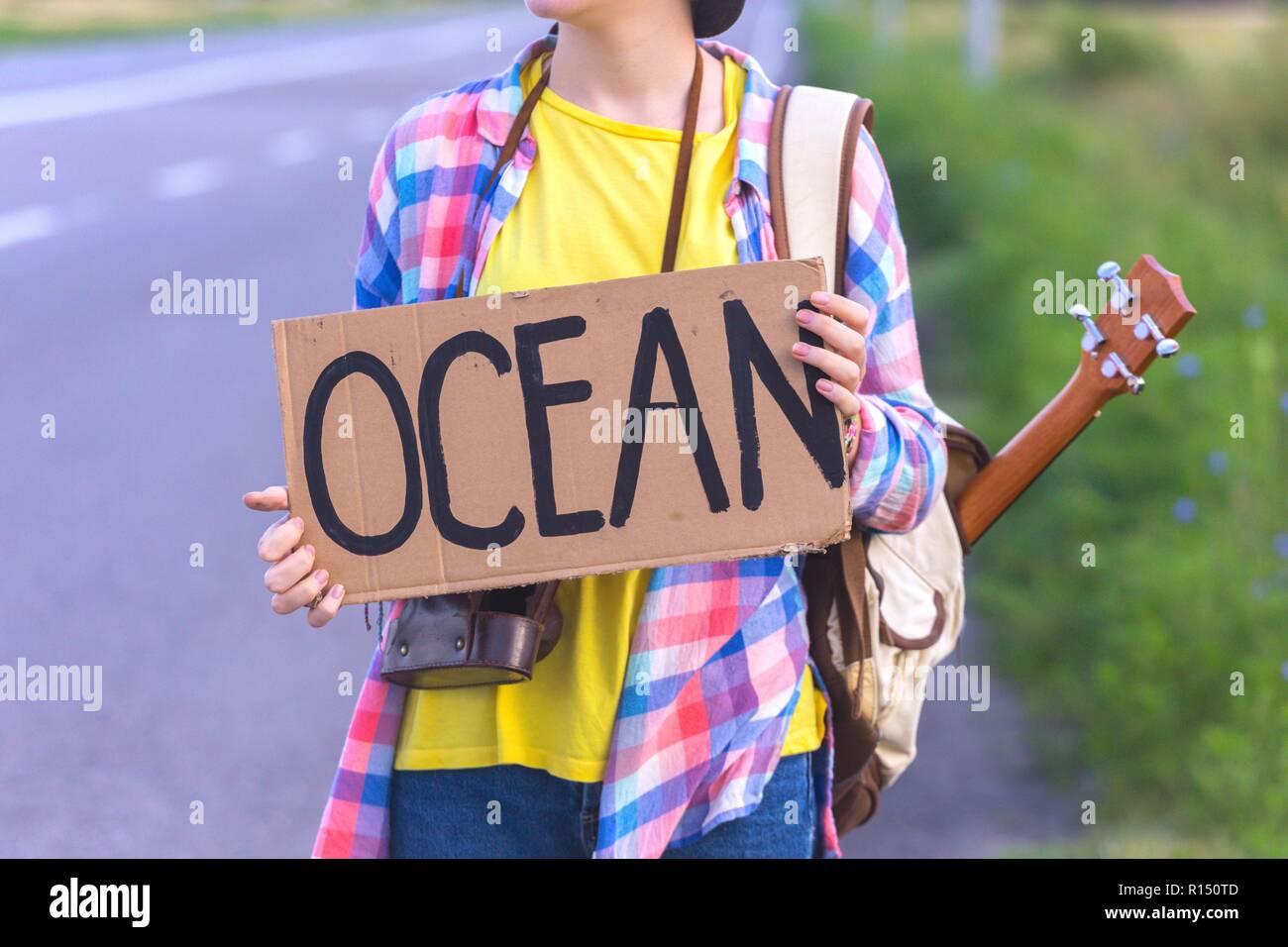 Ragazza giovane con una chitarra provenienti lungo la strada e il sollevatore-escursionismo Foto Stock