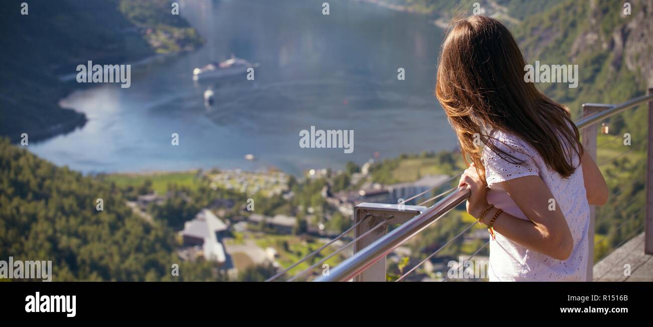 Ragazza guarda il Geirangerfjord e montagne da una piattaforma di osservazione, Norvegia Foto Stock