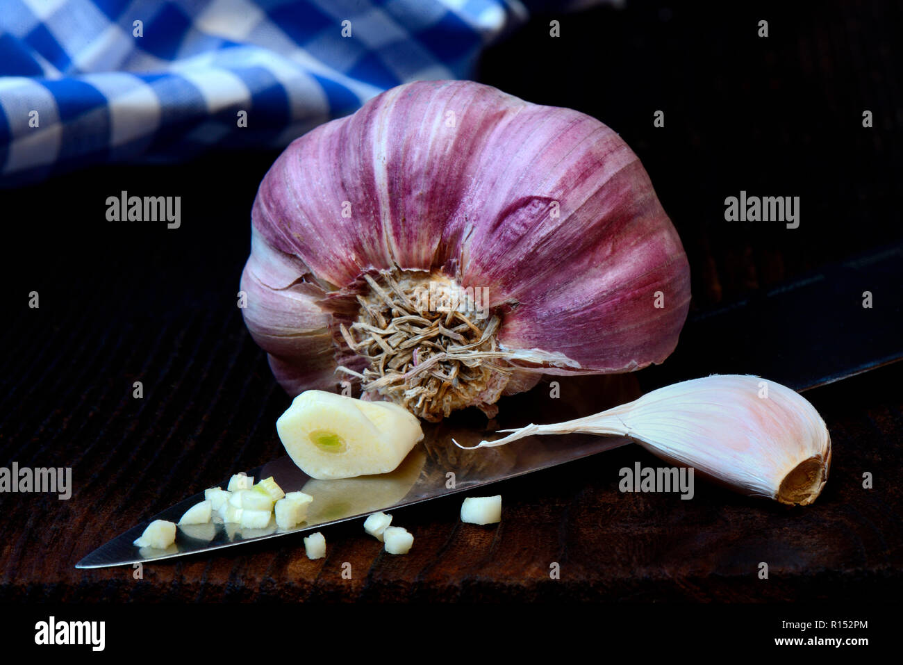 Knoblauchknolle und Knoblauchzehen auf Messer, Allium sativum Foto Stock