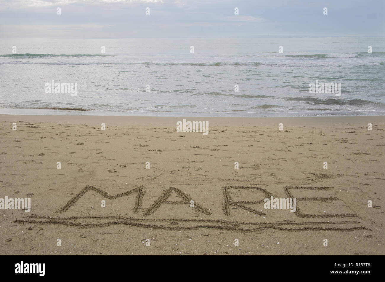 Mondo 'mare' mare in italiano scritto a mano ha sottolineato sulla sabbia acqua con piccole onde in background Foto Stock