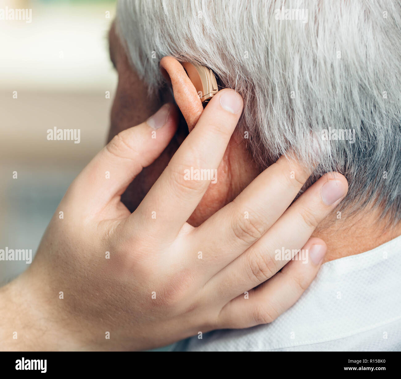 Il paziente è assistito in impostazione della protesi. Trattamento di audizione delle persone anziane usando un apparecchio auditivo. Foto Stock
