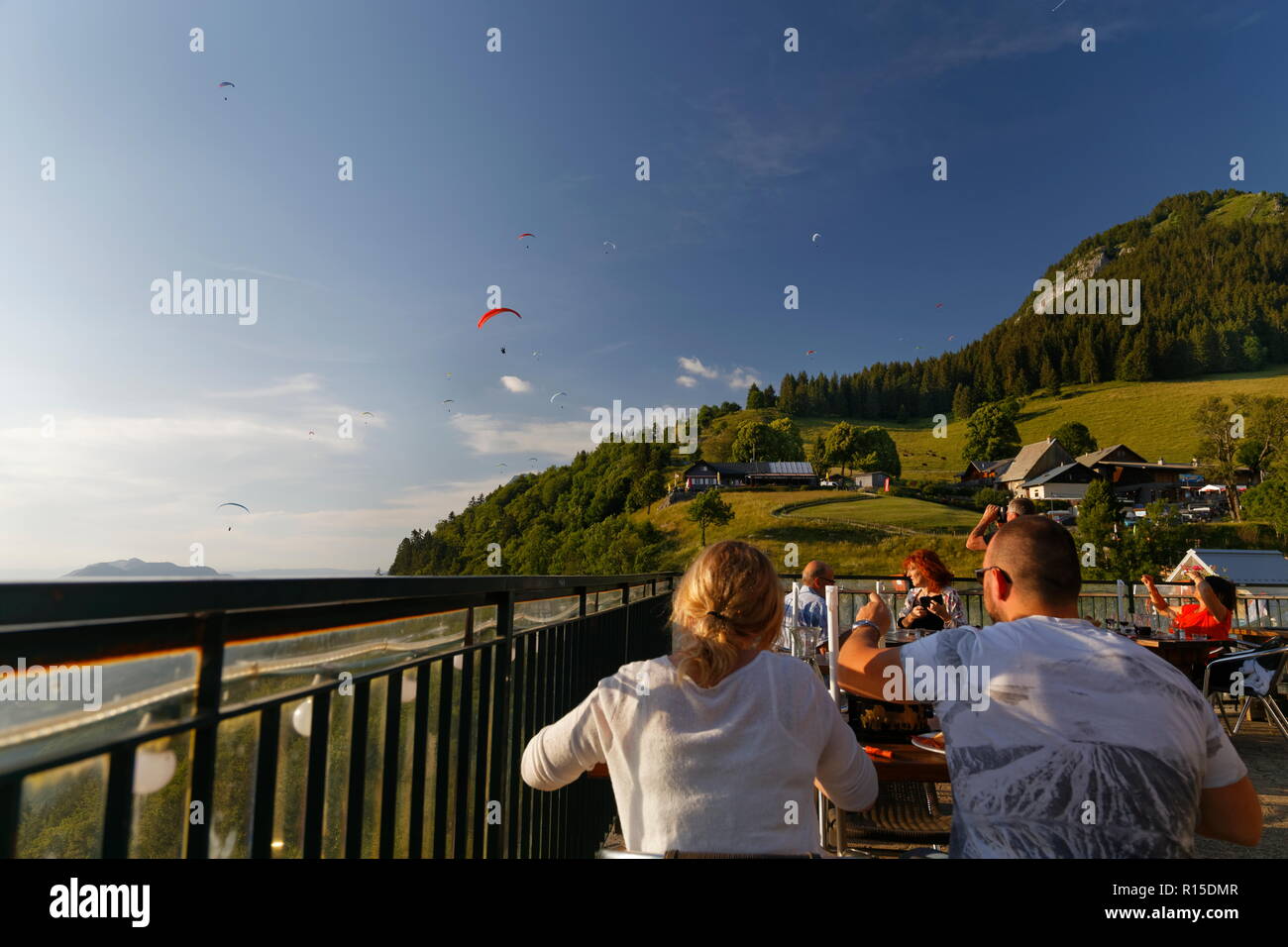 Vista di parapendio vola nel sole del tardo pomeriggio da uno dei ristoranti Col de la Forclaz sopra il lago di Annecy Francia Foto Stock