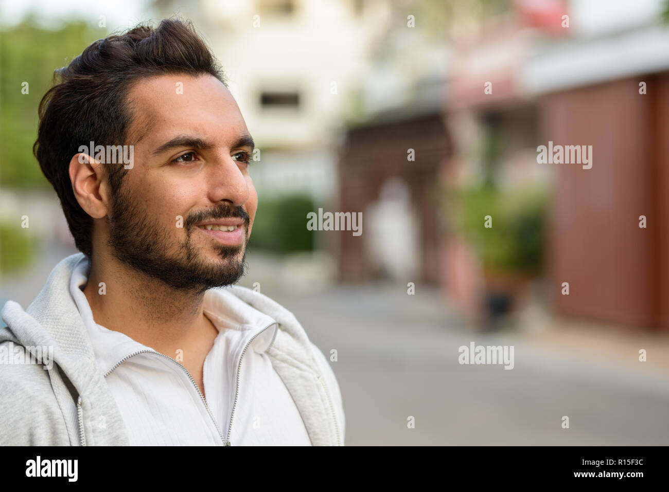 Ritratto di giovane felice uomo indiano pensando all'aperto Foto Stock