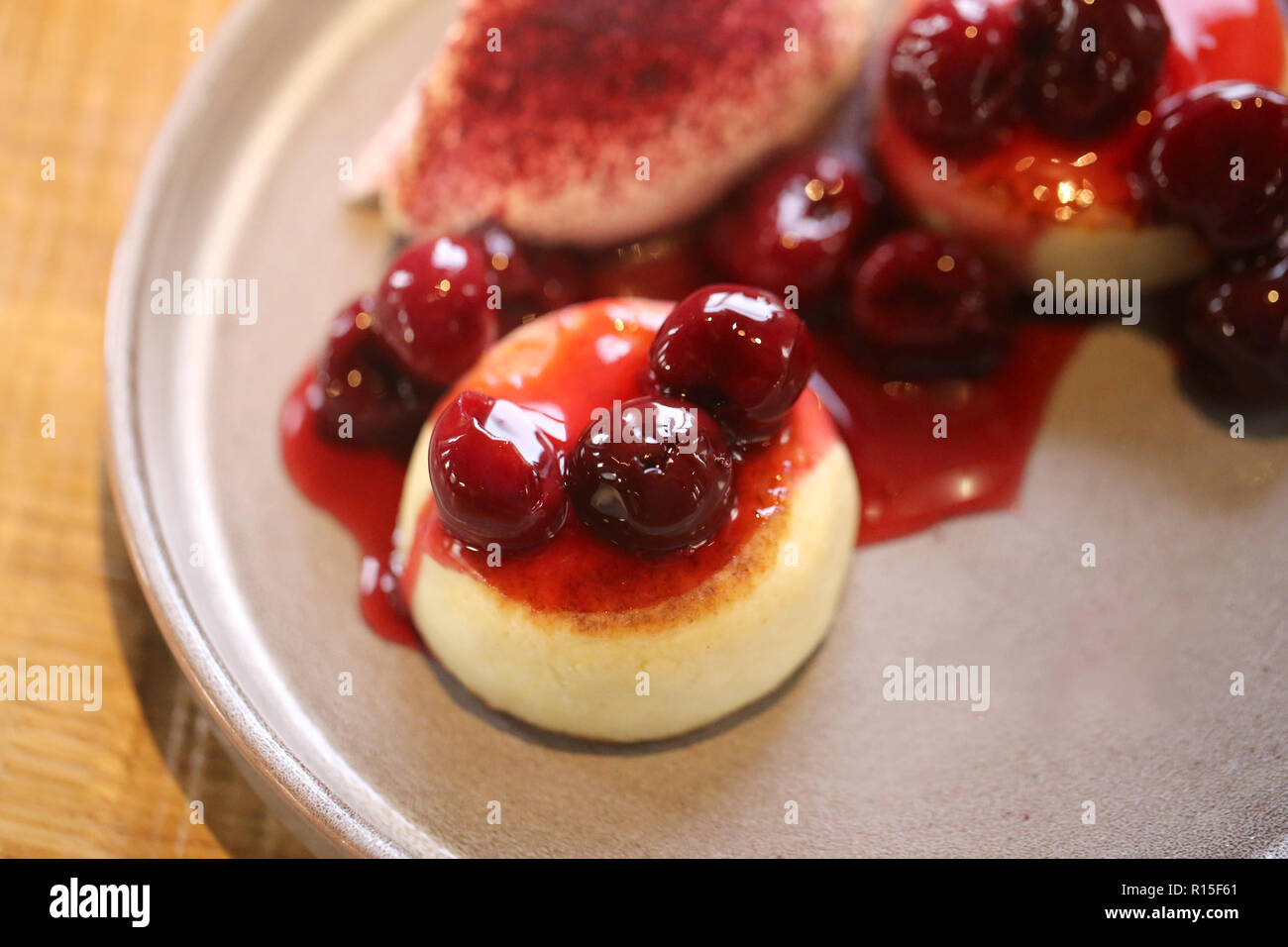 Foto macro di luminose deliziosi dolci di ricotta con marmellata di ciliege e panna acida su una piastra Foto Stock