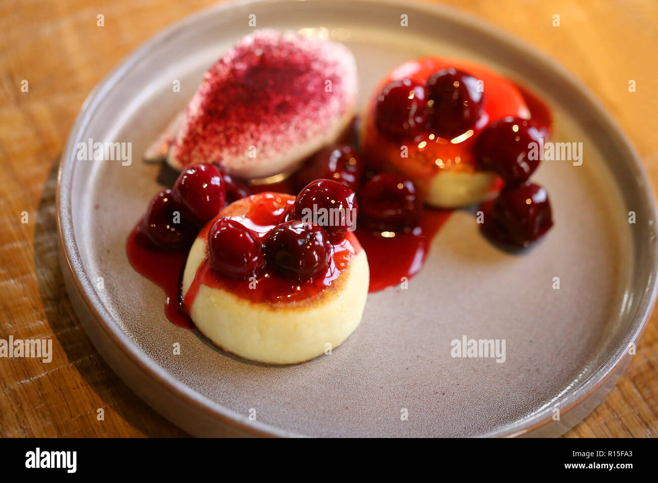 Foto macro di luminose deliziosi dolci di ricotta con marmellata di ciliege e panna acida su una piastra Foto Stock