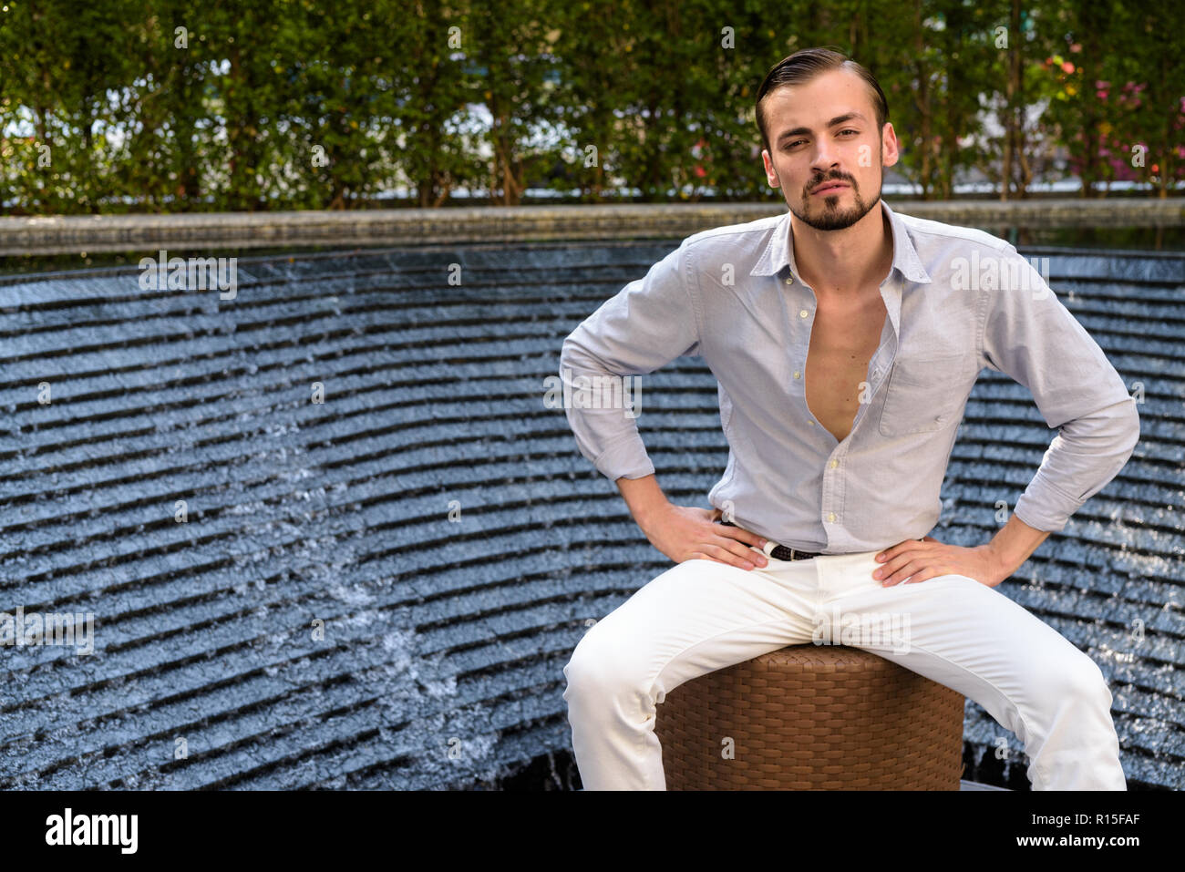 Ritratto di giovane barbuto di moda uomo seduto all'aperto Foto Stock