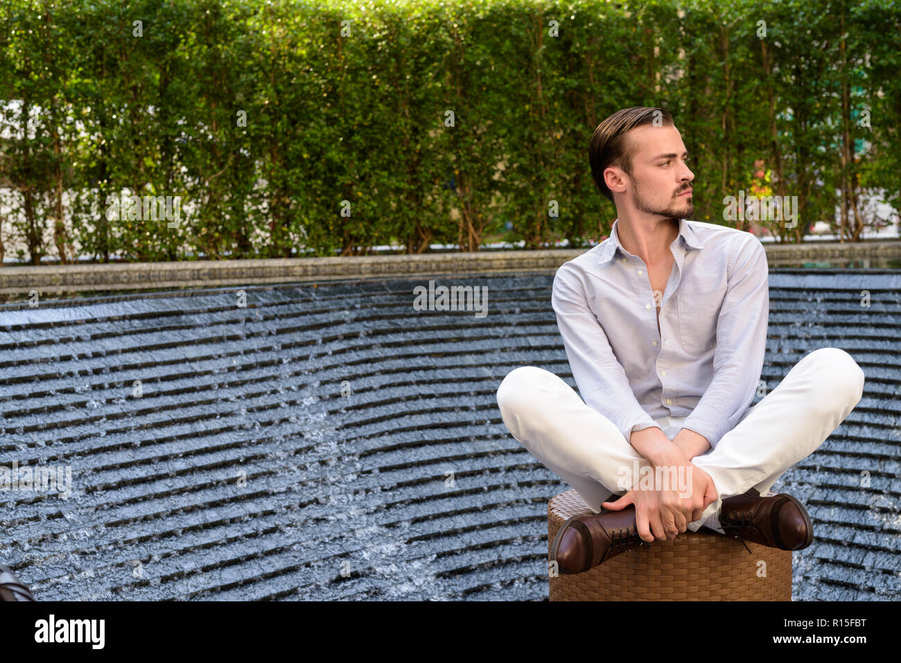 Ritratto di giovane imprenditore barbuto di relax presso il centro commerciale di Bangkok, Thailandia Foto Stock