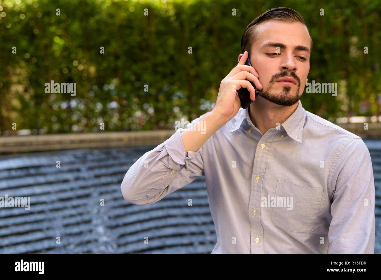 Ritratto di giovane barbuto di moda uomo che parla al telefono Foto Stock