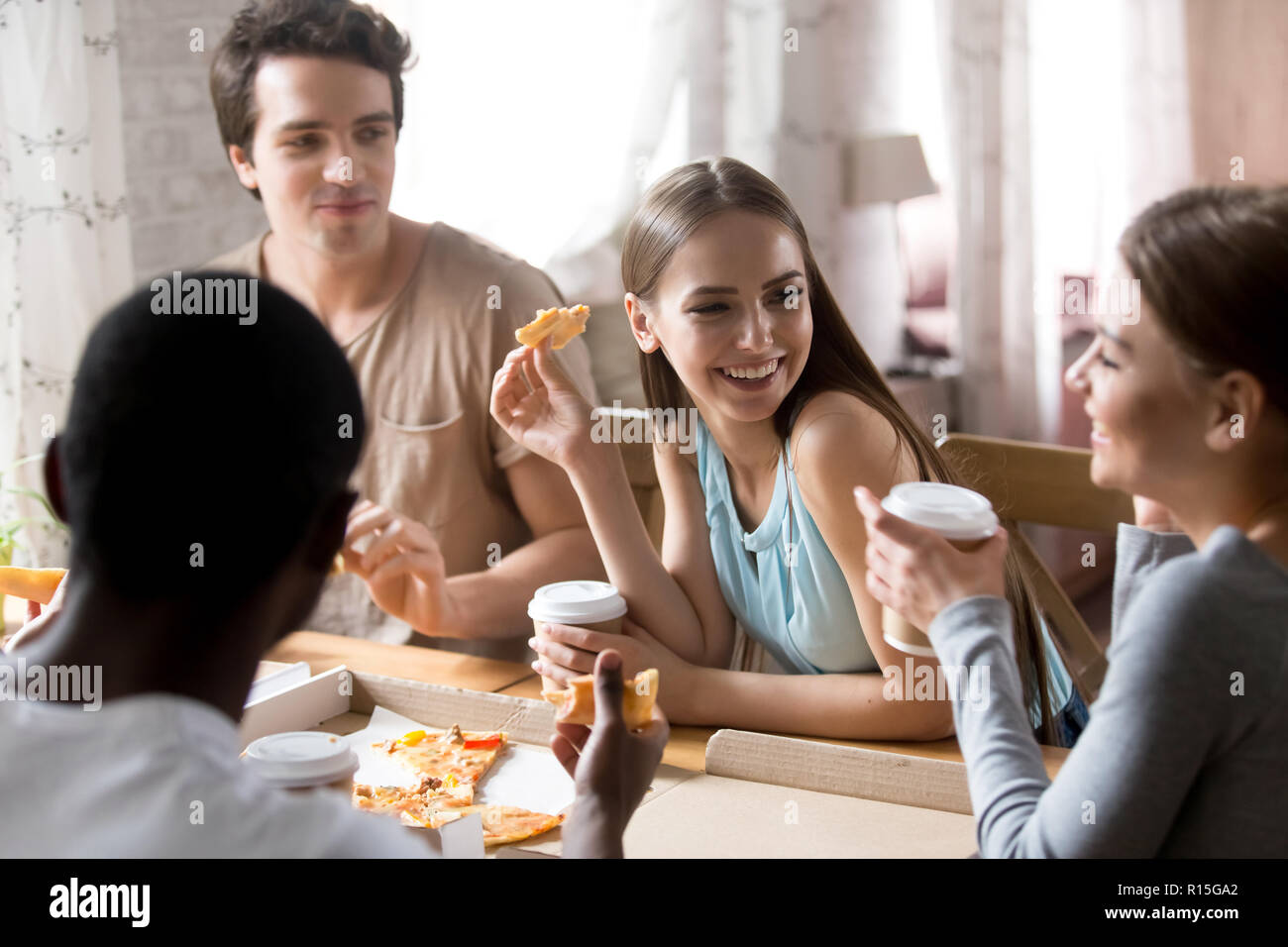 Diversi giovani allegro popolo millenario avente la cena seduta a tavola in pizzeria a mangiare la pizza si sente felice. Migliori amici radunati insieme la spesa Foto Stock